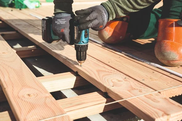 Person verschraubt Holzbretter mit Akkuschrauber